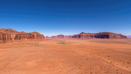 Fototapeta premium Wide-angle perspective of crimson rock formations in a desert landscape