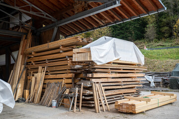 Stacks of timber planks and wooden boards stored under shed at carpentry workshop