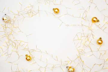 Golden baubles and warm fairy lights on white background. Bright festive layout with soft glow and copy space.