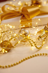 Christmas and New Year background with gift box, golden ribbon, garland and ornaments. Elegant composition with copy space for text or design.