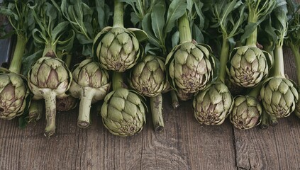 Obraz premium Freshly picked artichokes displayed on a vintage wooden surface, showcasing the charm of homegrown produce and the pleasure of traditional cooking
