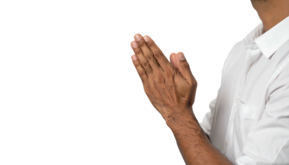Interlocked hands, praying or greeting, right of frame, against a solid dark backdrop. White shirt, side face visible