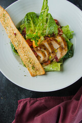 A delicious Caesar salad featuring grilled chicken breast, garnished with a crispy breadstick. This image showcases a healthy and appetizing meal