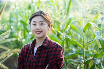 Young man farmer standing in corn field