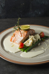A delectable salmon dish beautifully plated with fresh vegetables and a creamy sauce