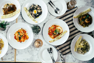 A top-down view of six exquisite plates of pasta and bread