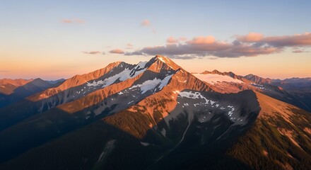 Majestic snow-capped mountain peaks and glaciers illuminated by golden hour light at sunset with soft clouds.