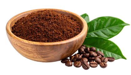 Close-up of a wooden bowl filled with ground coffee, beside coffee beans and green leaves on a black background