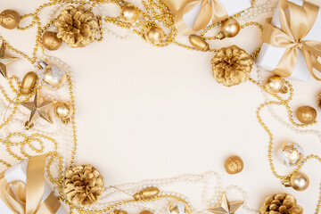 Golden Christmas and New Year frame with gifts, ornaments, pine cones, and pearls. Flat lay background with copy space for text or festive design.