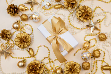 Golden Christmas and New Year frame with gifts, ornaments, pine cones, and pearls. Flat lay background with copy space for text or festive design.