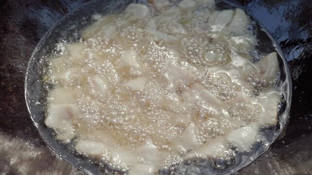 In slow motion, pieces of lamb tail fat melt and render in a hot cauldron outdoors during the first stage of traditional pilaf cooking, producing oil for frying other ingredients
