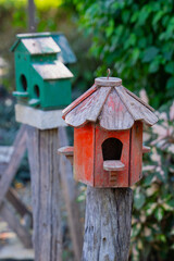 Rustic wooden birdhouses on weathered posts in garden setting, surrounded by lush greenery. scene evokes sense of tranquility and charm