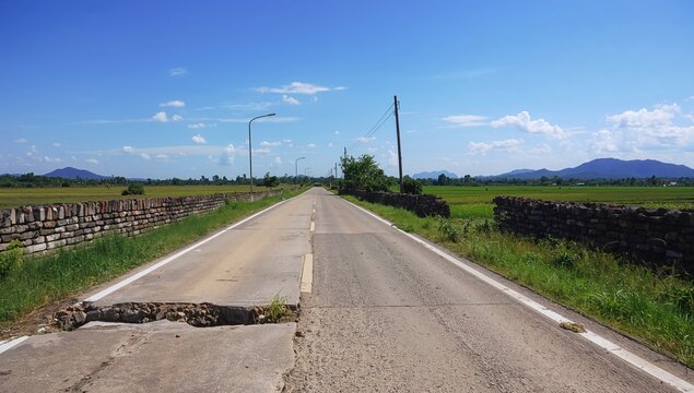 Worn-out pavement in rural area with textured surface and construction elements