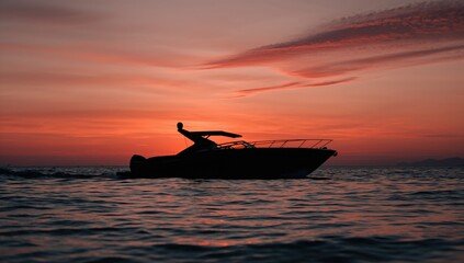 Obraz premium Silhouette of a speedboat against a sunset over the ocean