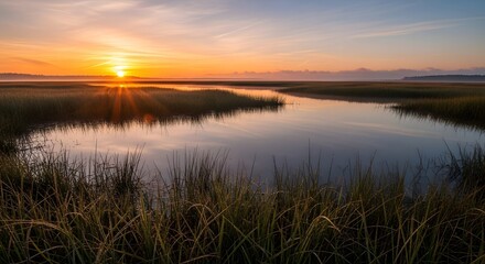Beautiful sunrise over a calm marsh with a river reflecting the sky