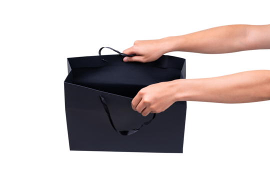 Hand holding black shopping bag isolated on transparent background