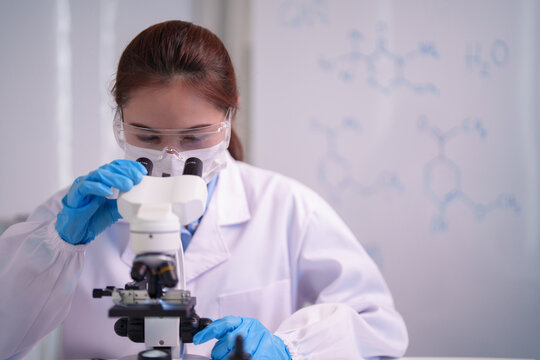 Asian adult woman scientist conducts laboratory research using microscope for scientific discovery medical advancement chemical analysis