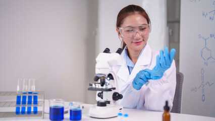 Asian female scientist prepares for chemistry experiment using microscope in laboratory conducting medical research for scientific discovery