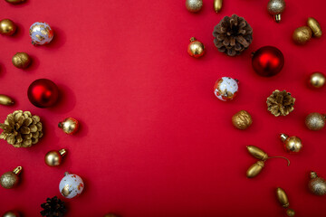 Red background with Christmas decorations on edges. Golden, red and white baubles, pinecones and nuts forming festive frame with copy space.