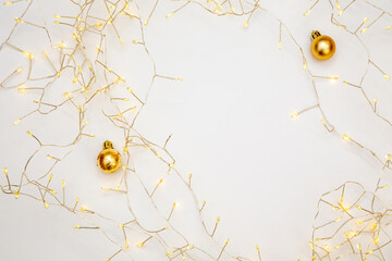 Golden baubles and warm fairy lights on white background. Bright festive layout with soft glow and...