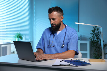 Fototapeta premium Doctor working on laptop at table in clinic during night shift