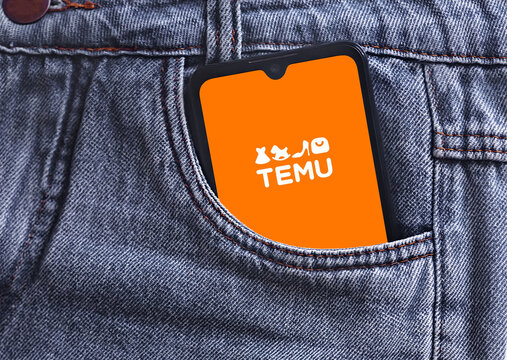 Temu logo on smartphone screen in jeans pocket. Temu logo online marketplace ecommerce on a smartphone