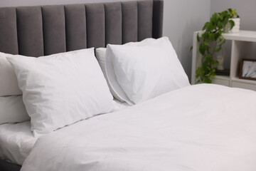 Large bed with linens and shelving unit near grey wall in bedroom