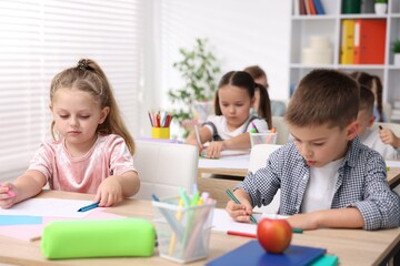 Fototapeta premium Cute children at wooden desks during art lesson in elementary school