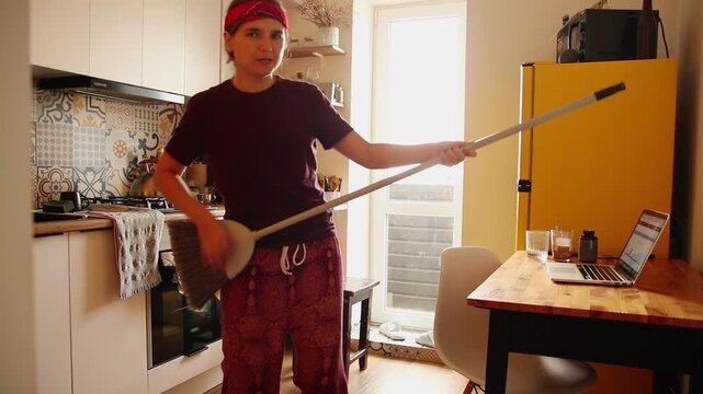 Hipster Woman Dancing and Singing While Cleaning the Kitchen. a hipster woman having fun while performing household chores
