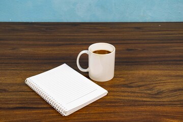 Spiral notebook and coffee mug on wooden desk for workspace planning