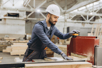 Carpenter cutting wooden planks using saw in workshop