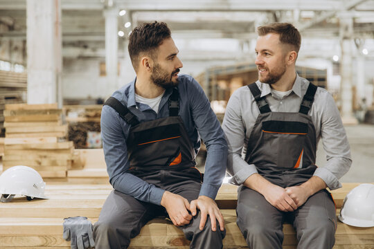 Two carpenters discussing in lumber warehouse: modular building industry