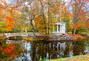 Late autumn in old public park, walking bridge and abandoned resting pergola