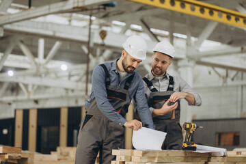 Construction workers discussing blueprint in modular building factory