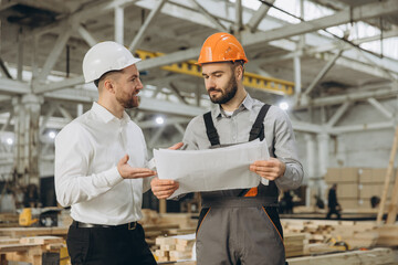 Engineers discussing blueprint in modular building factory