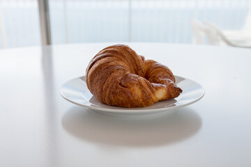 Cornetto dolce su piatto e tavolo bianco