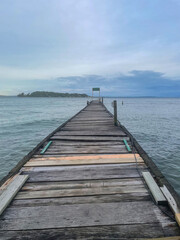Fototapeta premium A weathered wooden pier stretches into the calm Caribbean Sea near Bocas del Toro, Panama. Cloudy blue sky