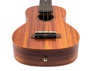 A close-up, focused view of a small, brown, wooden ukulele against a black background, highlighting its texture