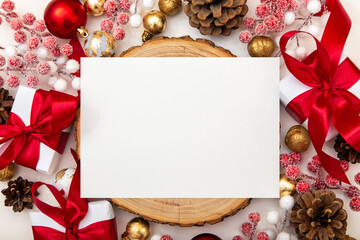 Advertising mockup with white paper in the center. Christmas baubles, pinecones and gifts create a festive atmosphere.