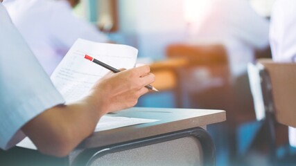 Students writing and reading exam answer sheets exercises in classroom of school with stress