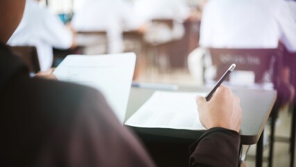 Students writing and reading exam answer sheets exercises in classroom of school with stress