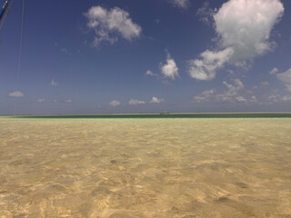 Fototapeta premium Crystal-clear turquoise waters lap onto a pristine white sand shoreline on Kiritimati (Christmas Island), Kiribati. This remote Pacific coral atoll is renowned for its untouched lagoons, world-class s