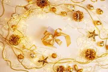 Fototapeta premium Christmas and New Year background with gift box, golden ribbon, garland and ornaments. Elegant composition with copy space for text or design.