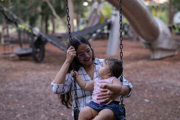 Beautiful mom and little daughter having fun on the swing