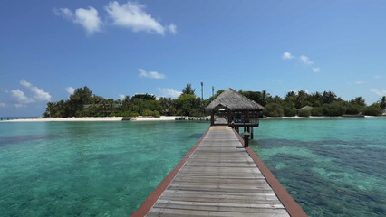 Luxury resort photo of Maldives tropical paradise island in Indian Ocean with palm trees, overwater thatched bungalows, wooden bridge. Beautiful photography, coral reef, azure ocean, sky with clouds. 