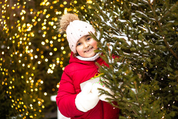 Cute little girl standing nearby Christmas tree snowy winter outside