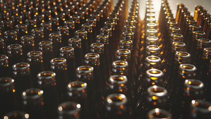 Fototapeta premium Brown glass bottles are processing on filling machine conveyors in a manufacturing plant, showing the repetition and mass production of beverages in a modern factory setting