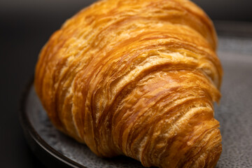 Close-Up of Golden Butter Croissant – Flaky Layers and Buttery Texture on Dark Plate