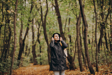 Woman with backpack hiking on footpath in autumn forest and relaxing outdoor.