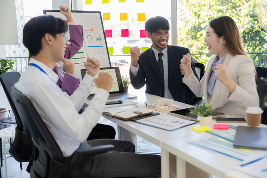 Teamwork concept of successful colleagues, multiethnic Asian team discussing business, clapping, laughing and smiling together in brainstorming meeting at office.